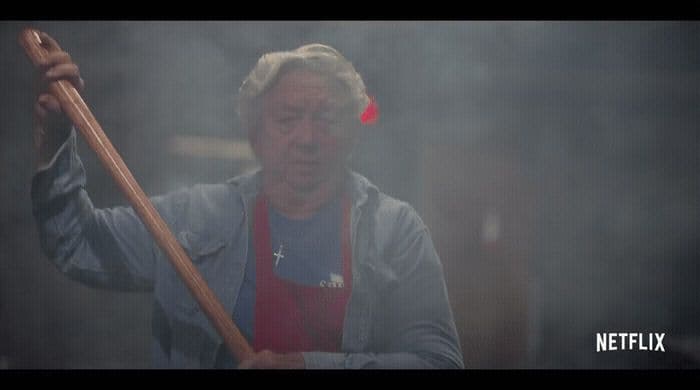 a man in an apron holding a wooden stick