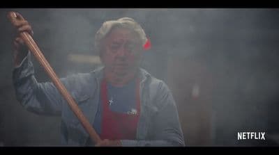 a man in an apron holding a wooden stick