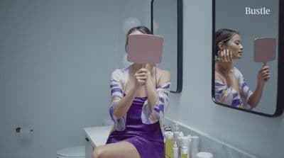 a woman in a purple dress sitting in front of a mirror