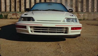 a white sports car parked in front of a fence