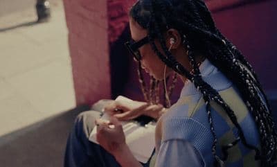 a woman with dreadlocks sitting on a bench looking at her cell phone
