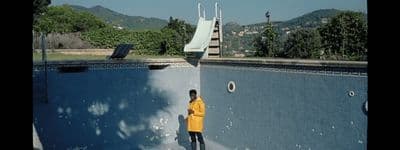 a man in a yellow jacket standing next to a swimming pool