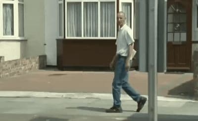 a man walking down a street past a building