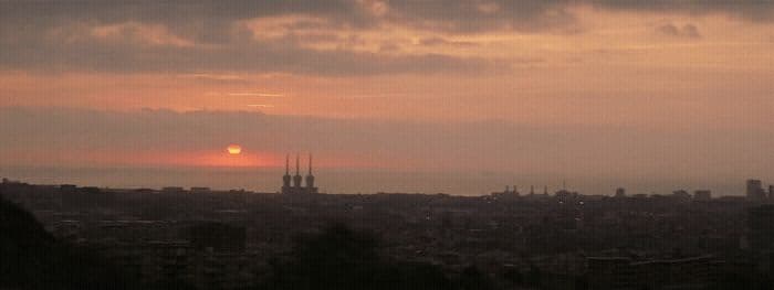 the sun is setting over a city with tall buildings