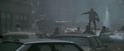 a man standing on top of a car in a parking lot