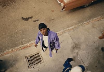 a person standing on a sidewalk with a car in the background
