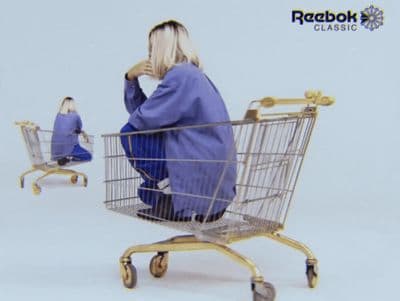 a woman sitting in a shopping cart in front of a mirror