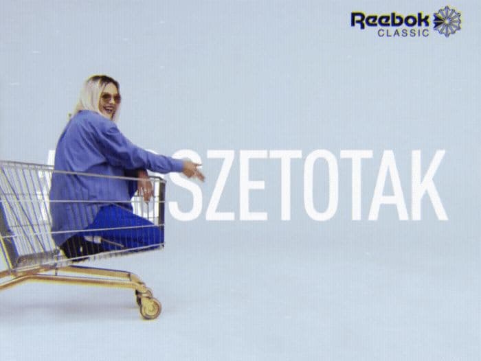 a woman sitting in a shopping cart with a sign behind her