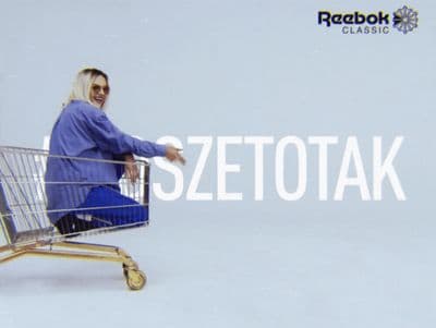 a woman sitting in a shopping cart with a sign behind her