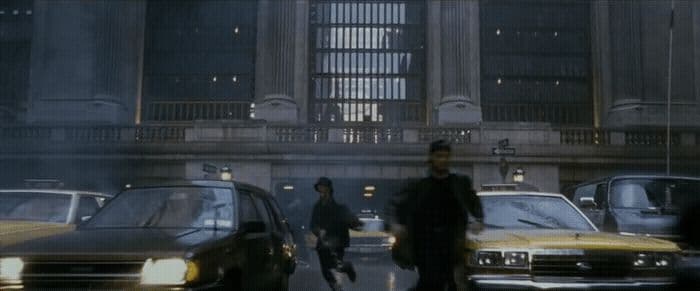 a group of people walking down a street next to parked cars