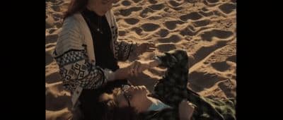 a group of people sitting on top of a sandy beach