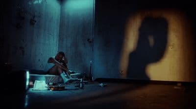 a woman sitting in a room with a shadow on the wall