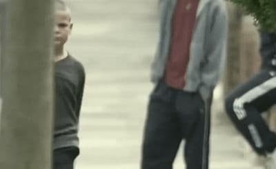 a man standing next to another man on a sidewalk