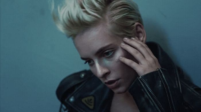 a woman in a leather jacket leaning against a wall