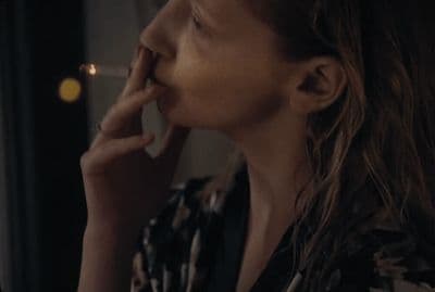 a woman with long hair is smoking a cigarette