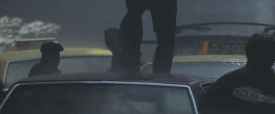 a man standing on top of a car in the rain