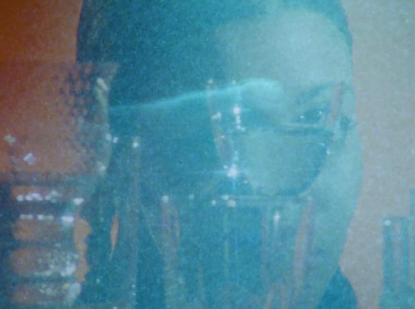 a reflection of a man with glasses in a room