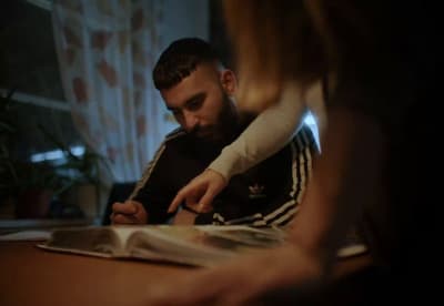 a man sitting at a table writing on a piece of paper
