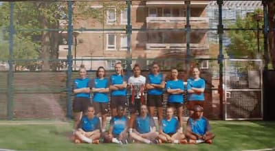 a group of people posing for a picture on a tennis court