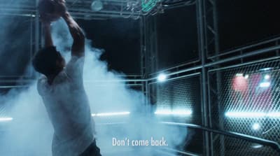 a man dunking a basketball in a smoke filled gym