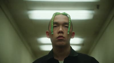a man with green hair standing in a hallway