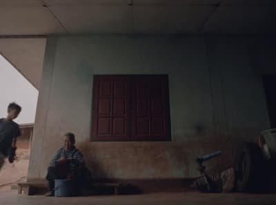 two men sitting on a bench in front of a building