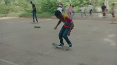 a young man riding a skateboard down a parking lot