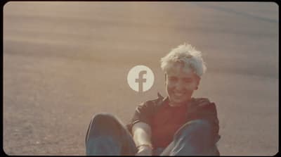 a man sitting on the ground with a facebook logo above his head