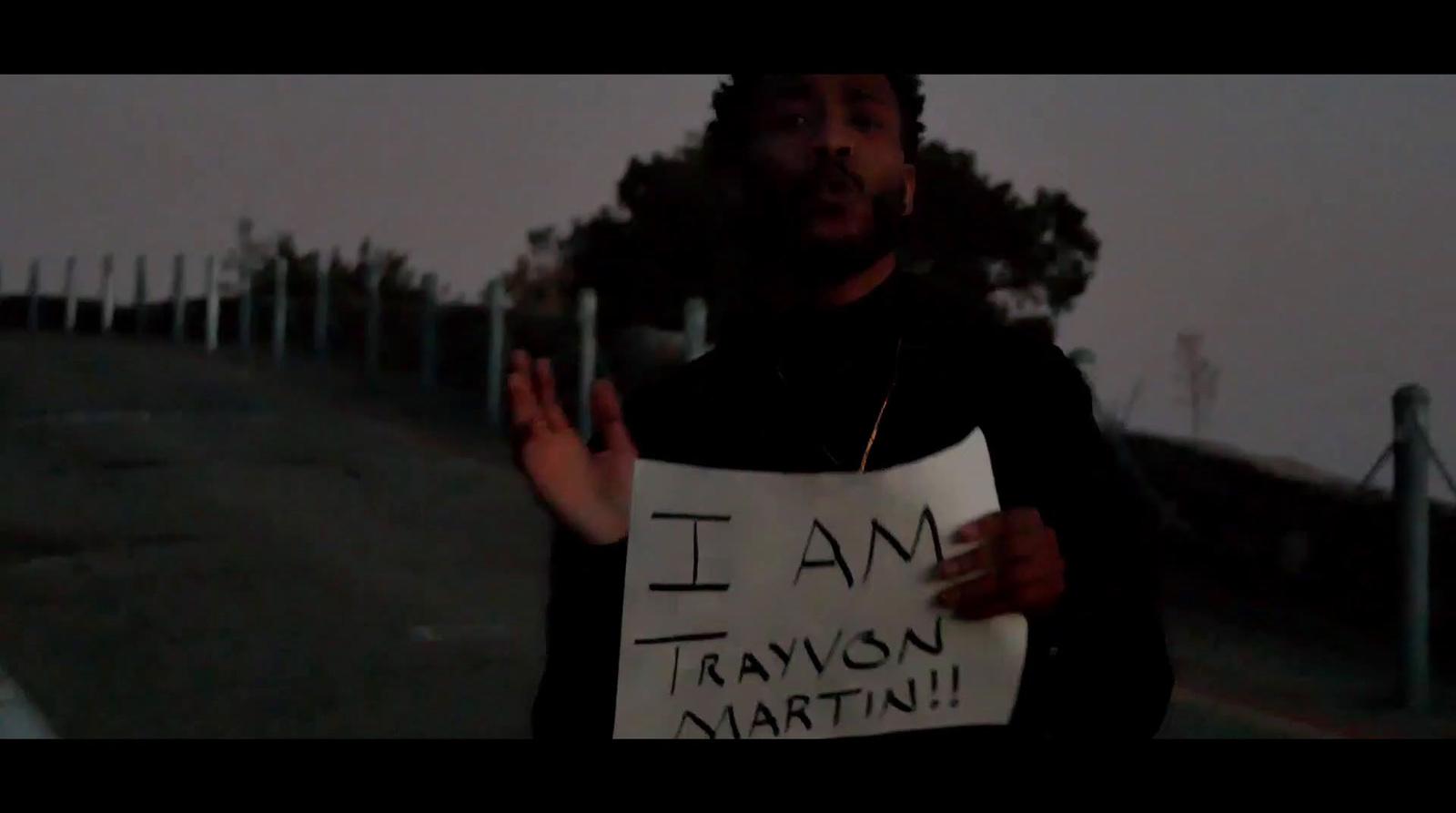 a man holding a sign that says i am travisson martin