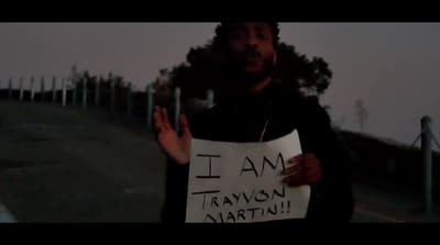 a man holding a sign that says i am travisson martin
