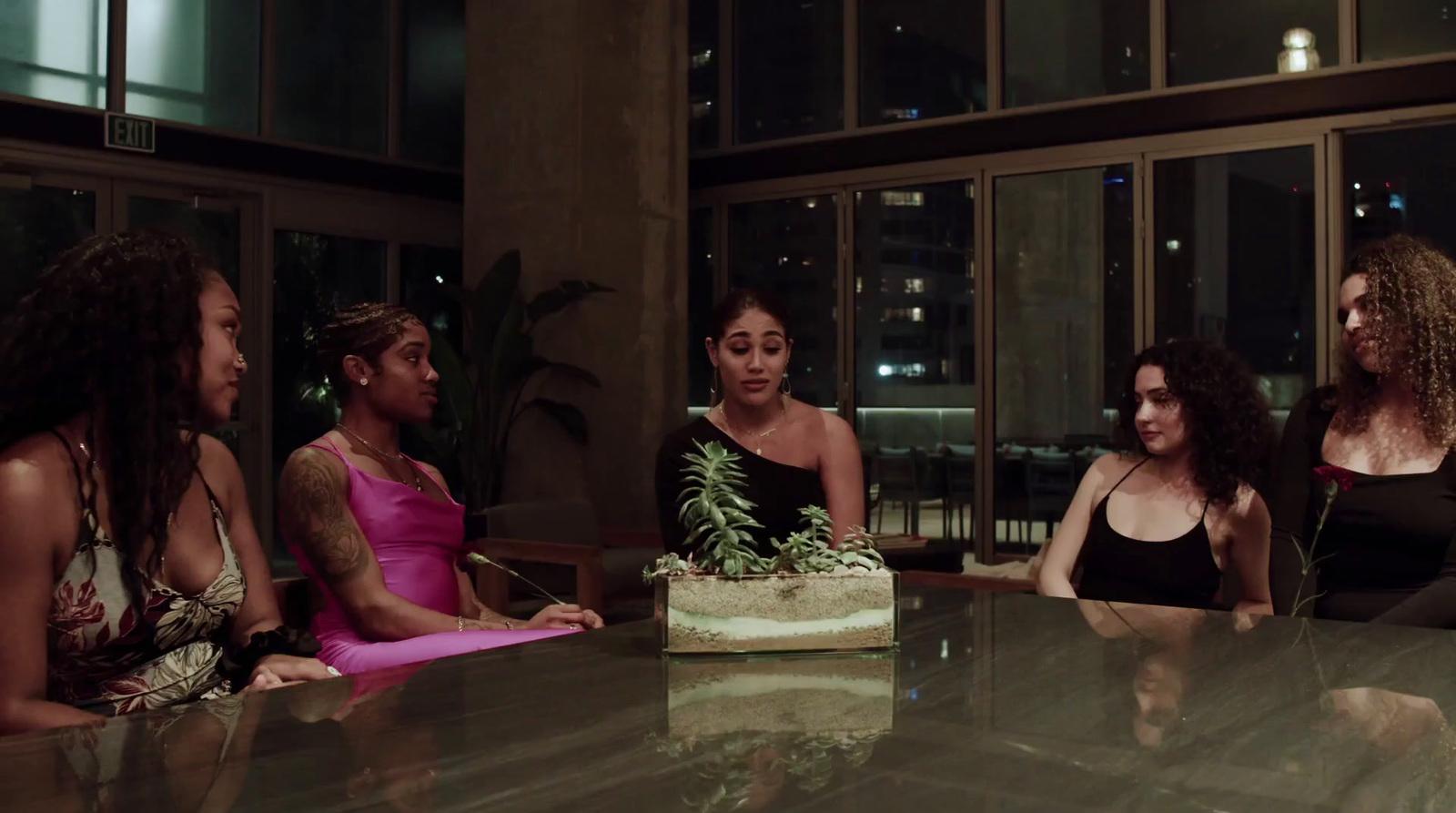 a group of women sitting around a table with a cake