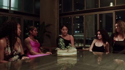 a group of women sitting around a table with a cake
