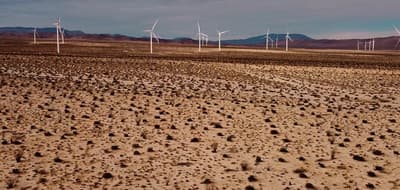 a large field of dirt with wind mills in the background