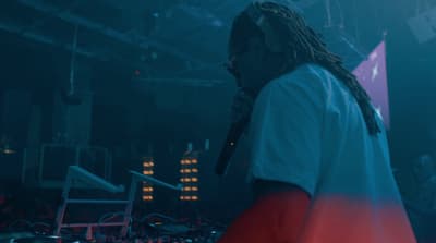 a man with dreadlocks standing in front of a dj set