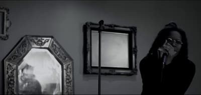 a woman standing in front of a mirror holding a microphone