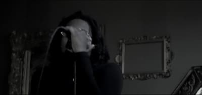 a woman standing in a dark room with her hands on her face