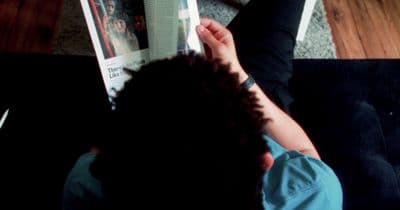 a person sitting on the floor reading a magazine