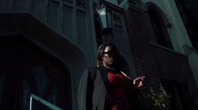 a woman in a red dress is standing outside a building