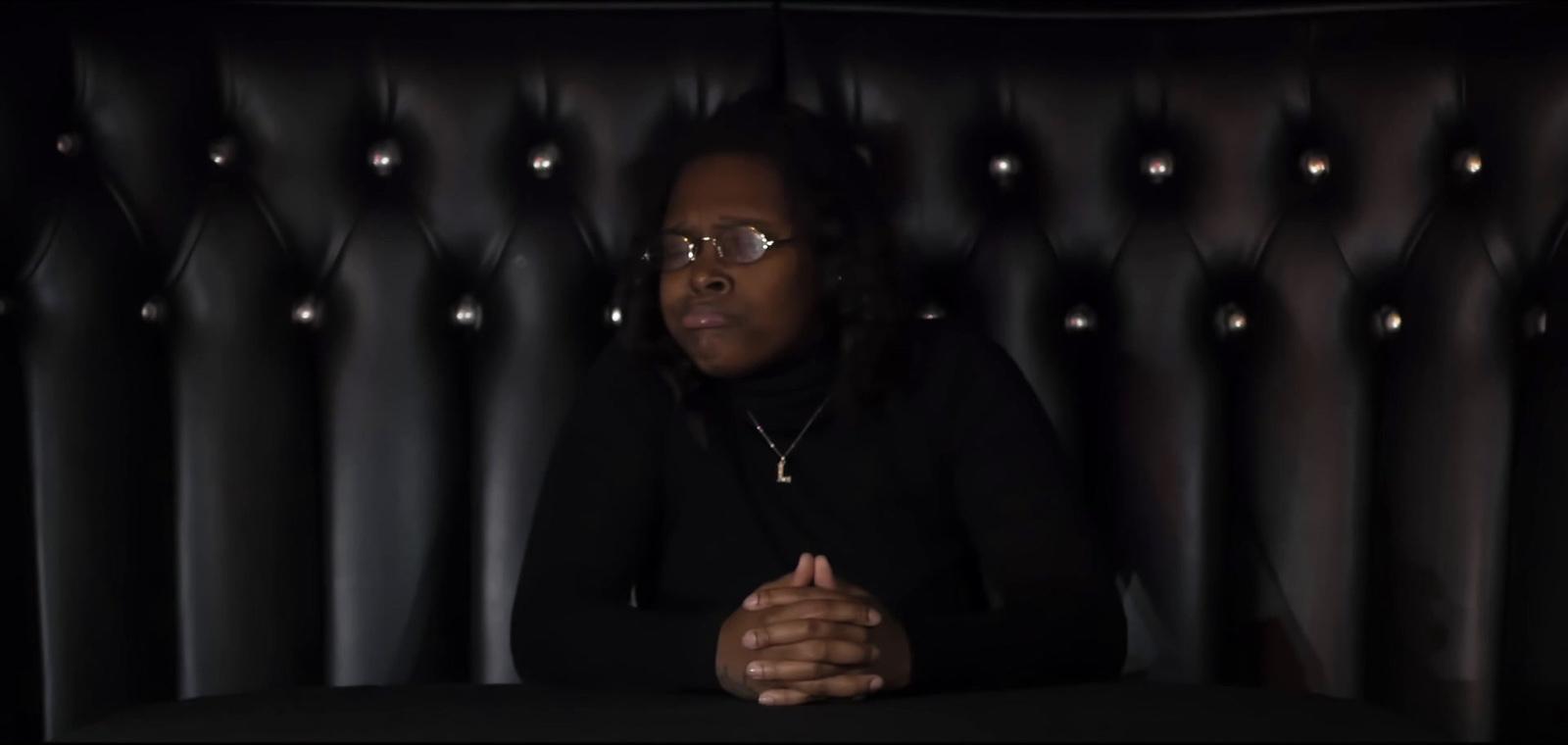 a woman sitting at a table in front of a black wall