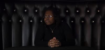 a woman sitting at a table in front of a black wall