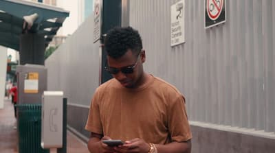 a man standing on a sidewalk looking at his cell phone