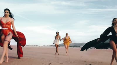 a group of women walking across a sandy beach