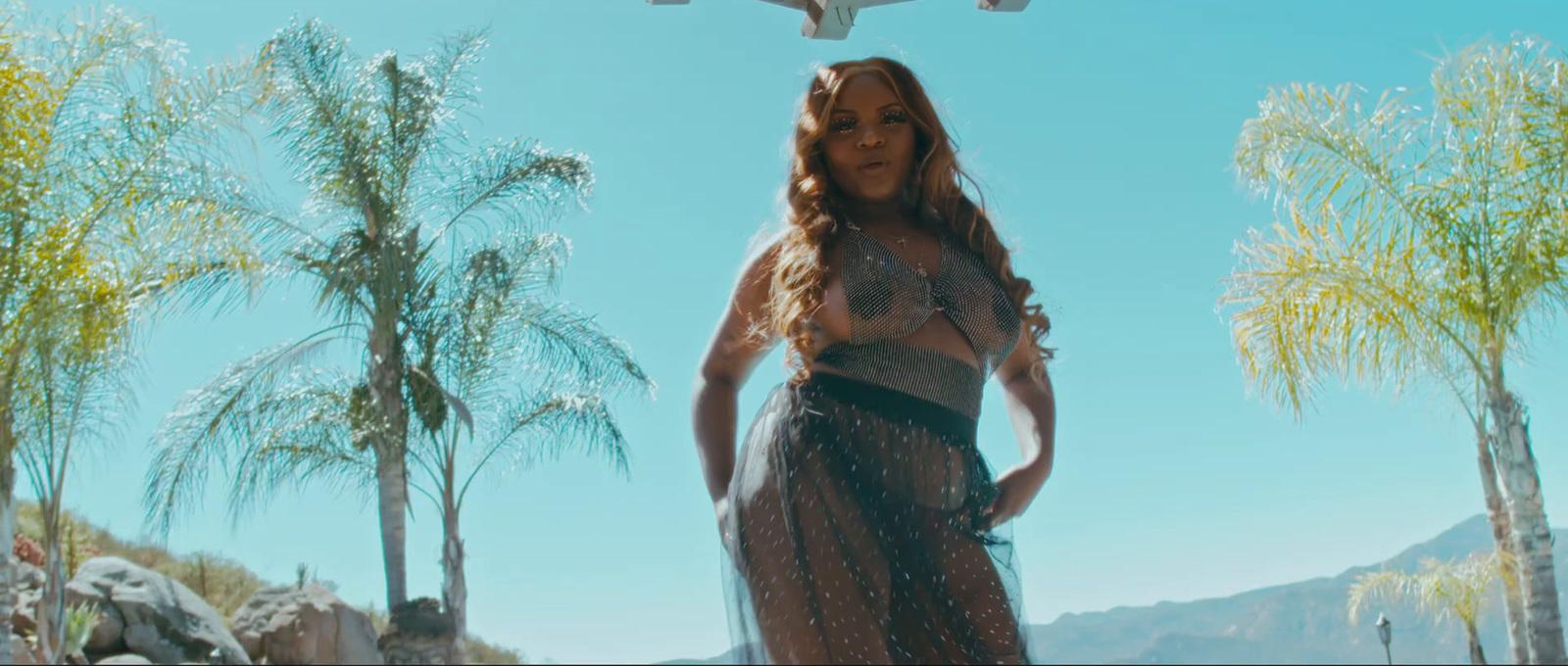 a woman in a long dress standing in front of palm trees