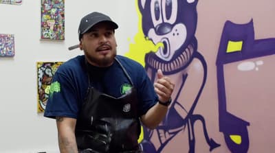a man in a black hat and apron holding a cigarette