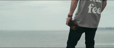 a man standing on a beach holding a purse