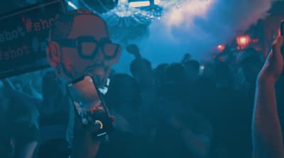 a man holding a skateboard in front of a crowd of people