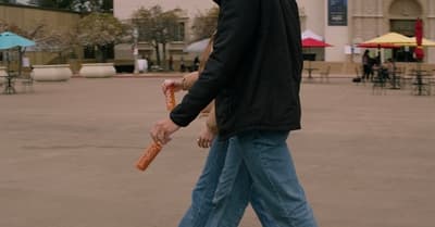 a man walking across a parking lot holding a baseball bat