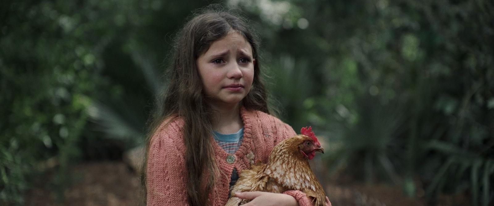 a little girl holding a chicken in the woods