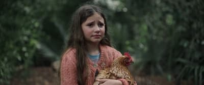 a little girl holding a chicken in the woods