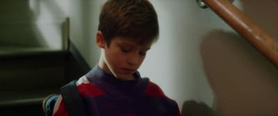a boy in a purple shirt is sitting on a stairway